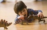 Mixed race boy playing with dinosaur toys